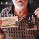 Liza Lizarraga’s father with photos of their ancestors and a house they lived in.